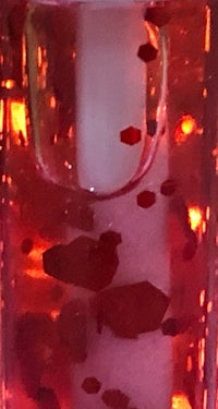 a close up of a bottle with red liquid in it